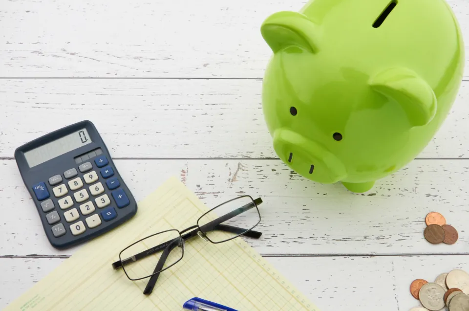 A calculator, notepad and piggy bank laid out for budgeting